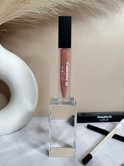 Lip gloss with a clear stand on a textured surface